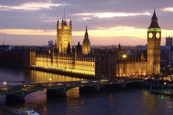 a large clock tower next to a body of water with Palace of Westminster in the background