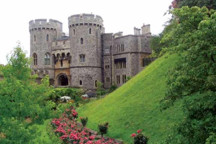 a castle on top of a lush green hillside with Windsor Castle in the background