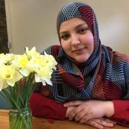 a person sitting at a table with a vase of flowers