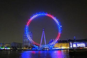 a large bridge lit up at night with London Eye in the background