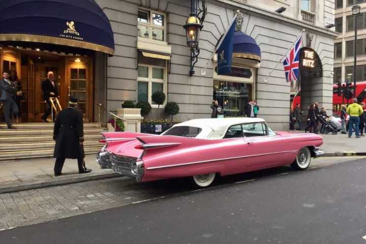 a group of people walking down a street next to a car