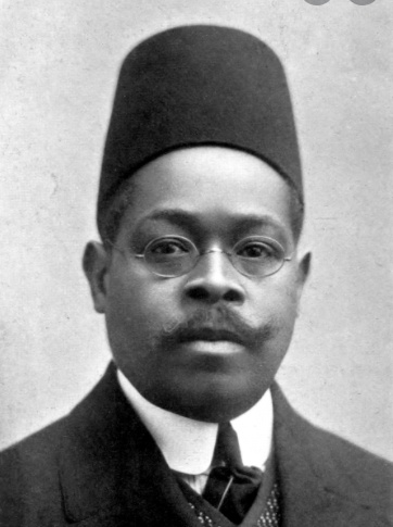 Dusé Mohamed Ali wearing a suit and tie