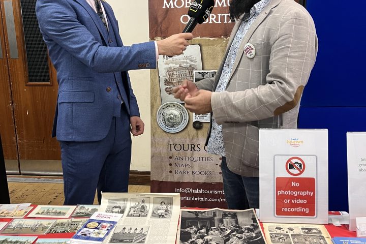 Two men at a table with historical photos and books on display.