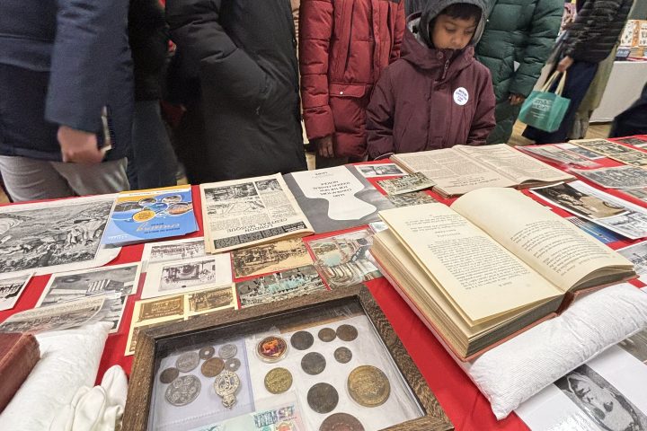 People viewing a table display of historical items at an indoor event.