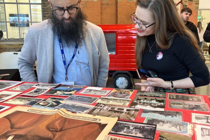 Two people examining historical photos on a table in an industrial-style room.