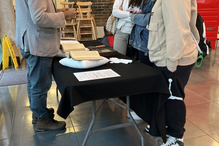 People interacting at a table with brochures in a casual setting.
