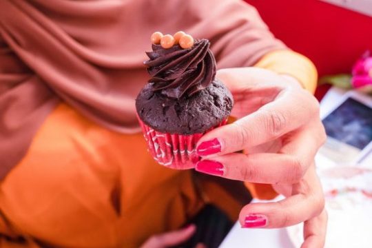 a person sitting at a table with a laptop and smiling at the camera