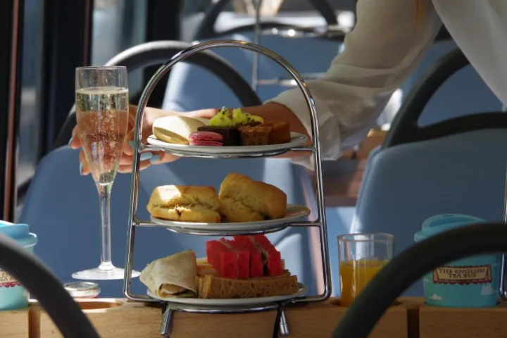 Afternoon tea setting with layered tray and champagne glass on a table.