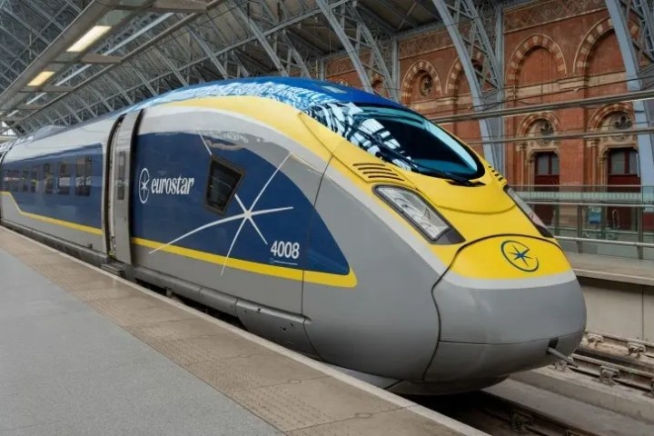 Eurostar high-speed train in station with arched glass roof and brick wall backdrop.