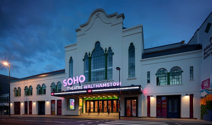 Exterior of Soho Theatre Walthamstow at night, illuminated sign and large arched windows.