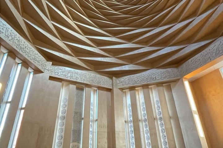 Interior of a modern mosque with geometric dome and tall windows.