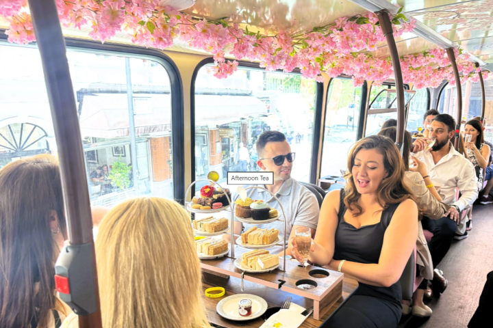People enjoying afternoon tea on a bus with pink floral decor.
