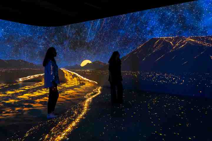 People in a room with immersive starry night and mountain projection.