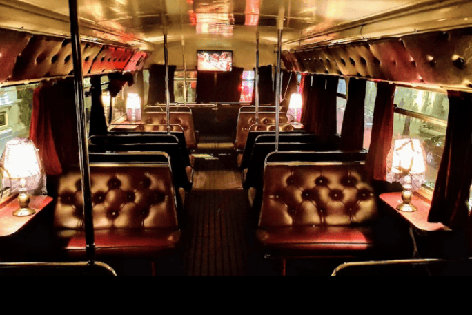 Vintage bus interior with leather seats and ambient lighting.