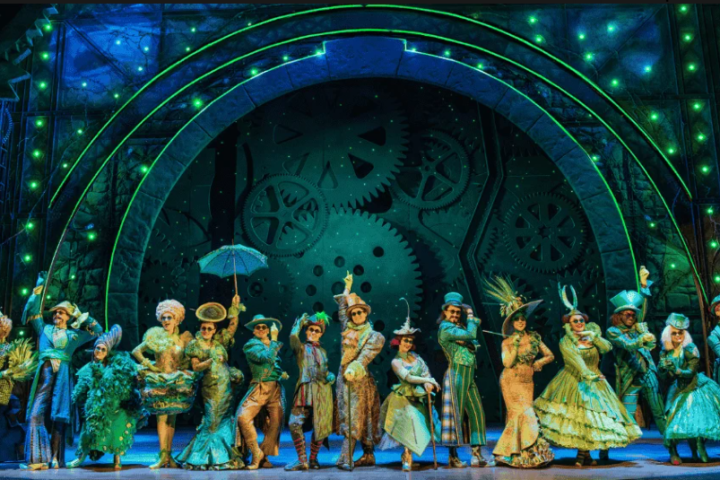 Theatrical stage with performers in period costumes and green lighting.